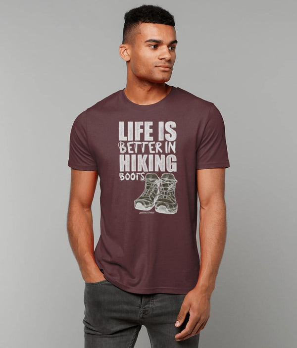 Male model wearing 'LIFE IS BETTER IN HIKING BOOTS' Print on Burgundy T-Shirt. Unisex/Women/Men. Certified Organic Clothing. Original Sketched Illustration by Artfully/Wild. Printed in the UK for hikers and mountain lovers.