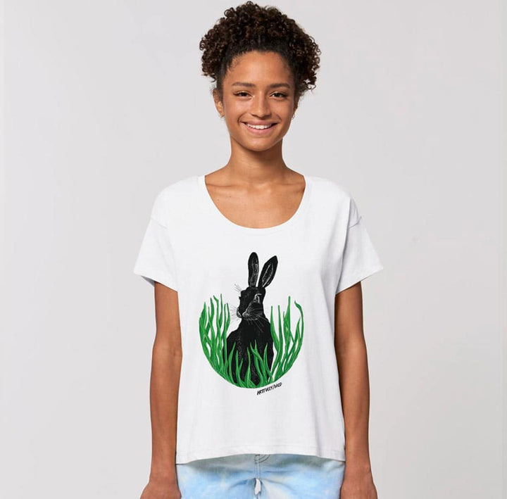 Female model wearing ‘HARE IN THE GRASS’ Print on Women’s White Scoop Neck Chiller T-Shirt. Original Illustration by Artfully/Wild. Printed with water-based inks in the UK for wildlife lovers.