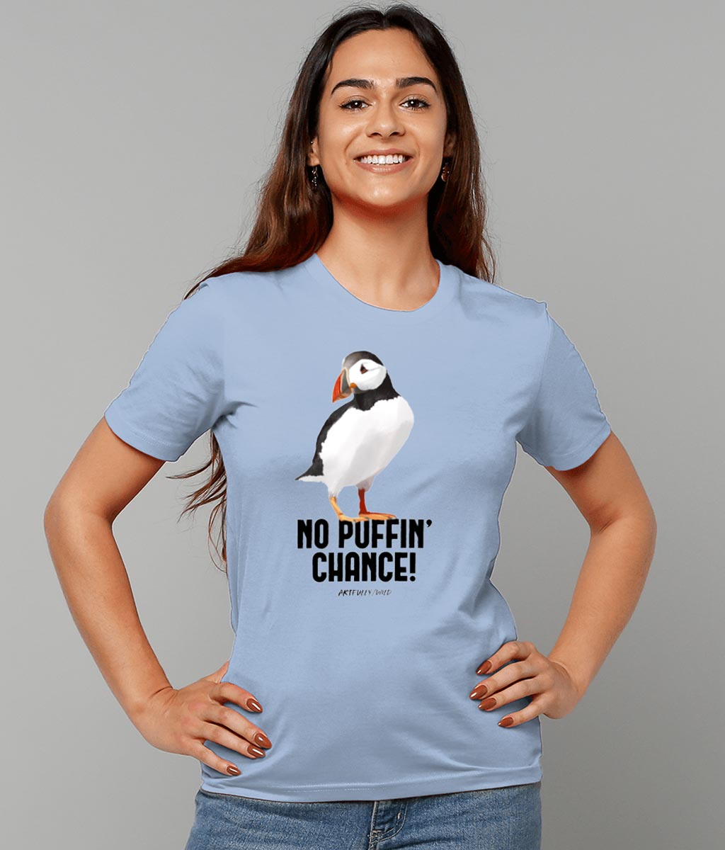 Female model wearing 'NO PUFFIN CHANCE' Print on Sky Blue Organic T-Shirt. Unisex/Women/Men. Ethical Clothing. Original Painted Illustration by Artfully/Wild. Printed with water-based inks.